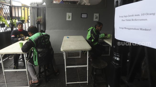 Sejumlah pengemudi ojek online menikmati hidangan makan gratis di Warung Makan Rakyat, Beji, Depok, Jawa Barat, Kamis (3/9/2020). [Suara.com/Angga Budhiyanto]