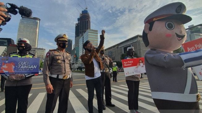 Dirlantas Polda Metro Jaya Kombes Pol Sambodo Purnomo Yogo (kiri) menemani Rian D'Masiv bernyanyi usai membagi-bagikan masker dan kantong PHBS dalam rangka kampanye penggunaan masker dan protokol kesehatan di Persimpangan Sarinah, Jakarta Pusat, Kamis (3/9/2020) [ANTARA/Livia Kristianti].