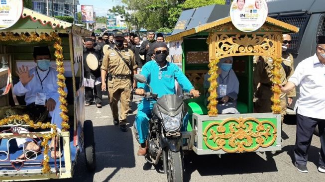 Isdianto-Suryani naik becak motor saat daftar Pilgub Kepri ke kantor KPU, Jumat (4/9). [ANTARA News/Ogen].