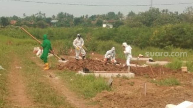 Para penggali kubur di TPU Buniayu, Kecamatan Sukamulya, Kabupaten Tangerang, tengah memakamkan jenazah Covid-19. [Suara.com/Ridsha Vimanda Nasution]