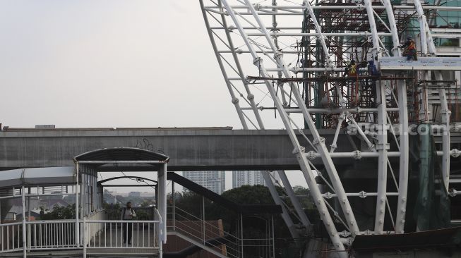 Pejalan kaki melintas di samping proyek pembangunan atap Stasiun Light Rail Transit (LRT) Jabodebek lintas pelayanan dua Cawang-Dukuh Atas di Jakarta, Sabtu (5/9/2020). [Suara.com/Angga Budhiyanto]