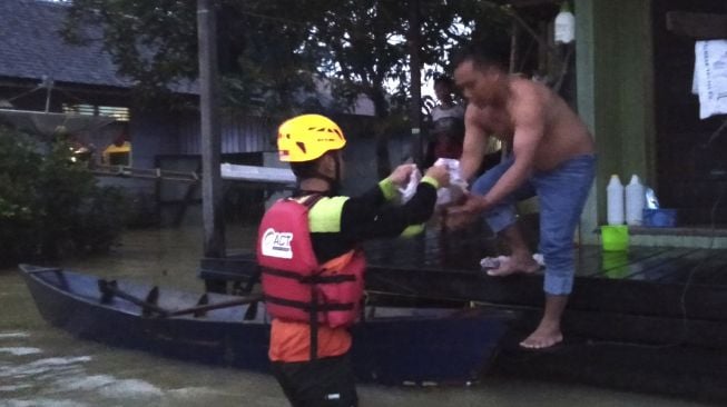 Relawan memberikan bantuan makanan kepada korban terdampak banjir di Desa Sinar Bulan, Kabupaten Tanah Bumbu, Kalimantan Selatan, Jumat (4/9/2020). [ANTARA FOTO/Toni-Relawan]