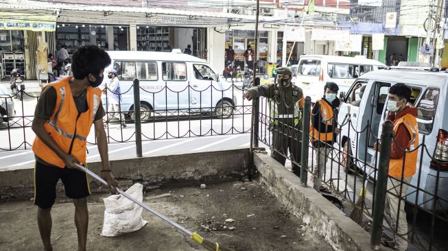 Warga yang melanggar aturan protokol kesehatan COVID-19 menyapu sampah saat terjaring Operasi Tertib Masker di kawasan Kampung Melayu, Jakarta, Senin (7/9/2020).  [ANTARA FOTO/Aprillio Akbar]