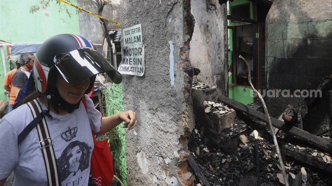 Warga melintas di samping sisa kebakaran yang melanda permukiman di Kelurahan Bali Mester, Kecamatan Jatinegara, Jakarta, Selasa (8/9/2020). [Suara.com/Angga Budhiyanto]