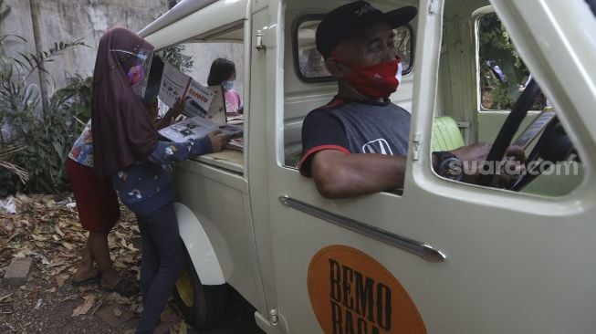 Sejumlah anak membaca buku koleksi dari Bemo Baca milik Sutino (60) bertepatan dengan Hari Aksara Internasional (HAI) di Jakarta, Selasa (8/9/2020). [Suara.com/Angga Budhiyanto]