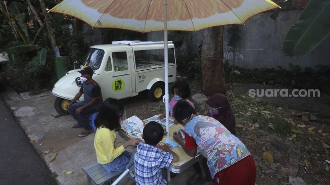 Sejumlah anak membaca buku koleksi dari Bemo Baca milik Sutino (60) bertepatan dengan Hari Aksara Internasional (HAI) di Jakarta, Selasa (8/9/2020). [Suara.com/Angga Budhiyanto]