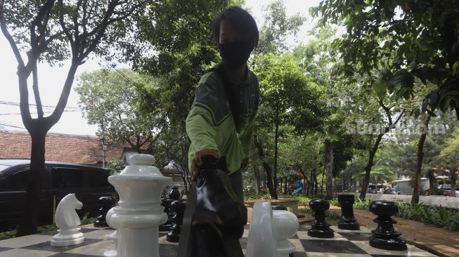 Petugas Sudin Pertamanan dan Kehutanan Jakarta Pusat bermain catur raksasa di sela-sela waktu istirahatnya di Taman Danau Singkarak, Bendungan Hilir, Jakarta, Rabu (9/9/2020). [Suara.com/Angga Budhiyanto]