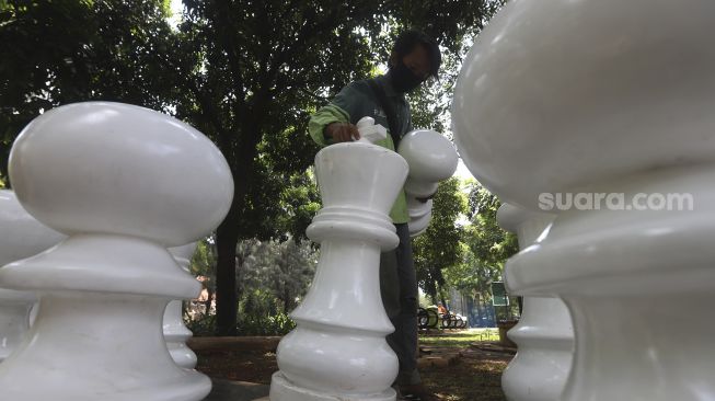 Petugas Sudin Pertamanan dan Kehutanan Jakarta Pusat menata bidak catur raksasa di Taman Danau Singkarak, Bendungan Hilir, Jakarta, Rabu (9/9/2020). [Suara.com/Angga Budhiyanto]