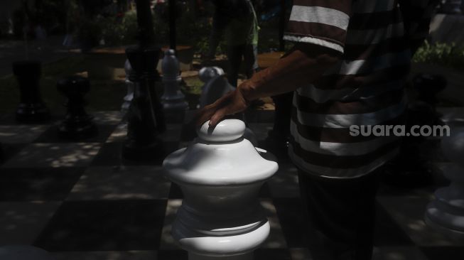 Petugas Sudin Pertamanan dan Kehutanan Jakarta Pusat bersama warga bermain catur raksasa di sela-sela waktu istirahatnya di Taman Danau Singkarak, Bendungan Hilir, Jakarta, Rabu (9/9/2020). [Suara.com/Angga Budhiyanto]