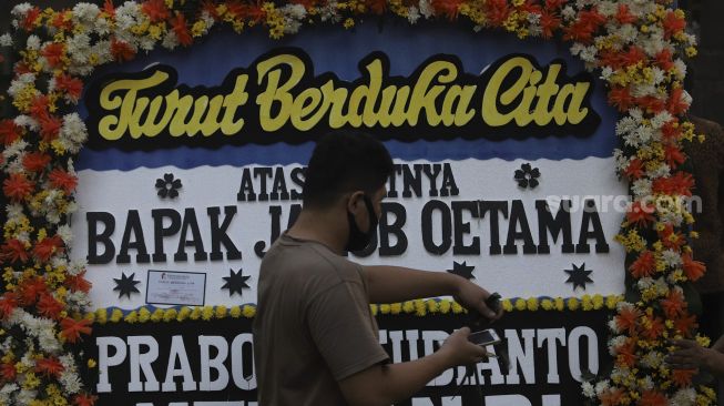 Petugas merapikan karangan bunga tanda berduka cita atas meninggalnya almarhum Pendiri Kompas Gramedia/ Pemimpin Umum Harian Kompas Jakob Oetama di rumah duka di jalan Sriwijaya, Jakarta, Rabu (9/9/2020). [Suara.com/Angga Budhiyanto]
