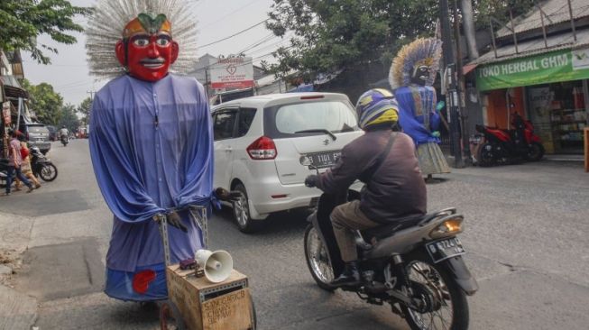 Pengamen Ondel-Ondel menari melintasi Jalan Raya Keadilan, Depok, Jawa Barat, Selasa (25/9/2019). [ANTARA/Yulius Satria Wijaya]