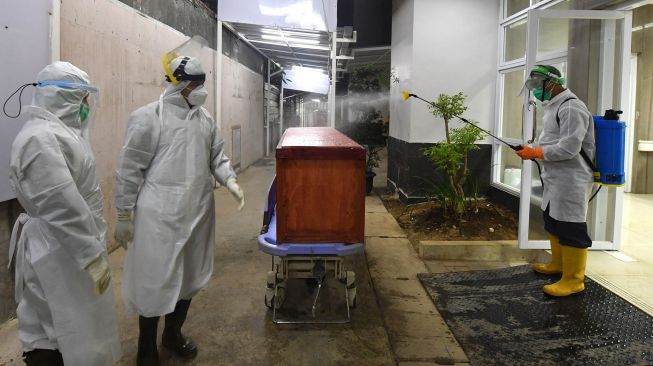 Petugas medis menyemprotkan desinfektan di atas peti mati pasien yang meninggal dunia karena virus Corona COVID-19, di Rumah Sakit Umum Bogor di Bogor, Jawa Barat, Rabu (9/9). [ADEK BERRY / AFP]
