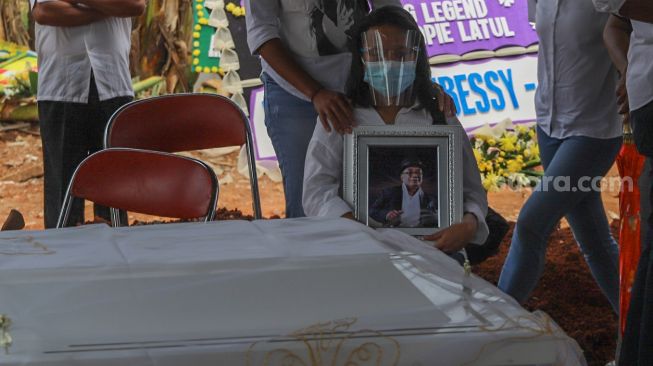 Keluarga memegang bingkai foto Penyanyi Yopie Latul saat jenazah tiba di TPU Tanah Kusir, Jakarta Selatan, Kamis (10/9). [Suara.com/Alfian Winanto]