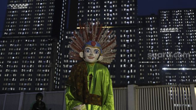 Ondel-ondel melintas di depan Rumah Sakit Darurat Penanganan COVID-19 Wisma Atlet Kemayoran, Jakarta, Kamis (10/9/2020). [Suara.com/Angga Budhiyanto]