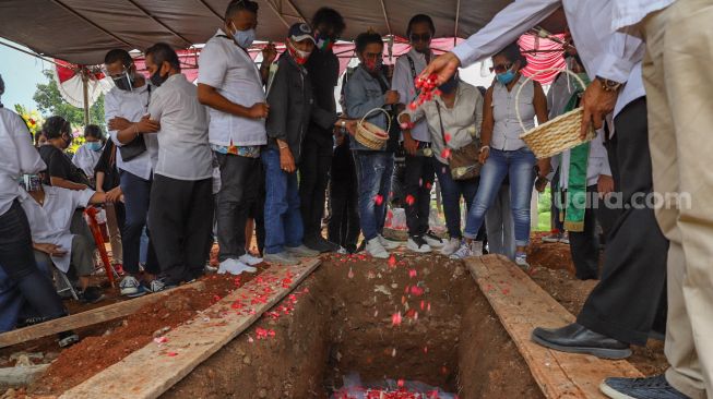 Keluarga dan kerabat menabur bunga di atas peti jenazah Penyanyi Yopie Latul sebelum ditutup tanah di TPU Tanah Kusir, Jakarta Selatan, Kamis (10/9). [Suara.com/Alfian Winanto]