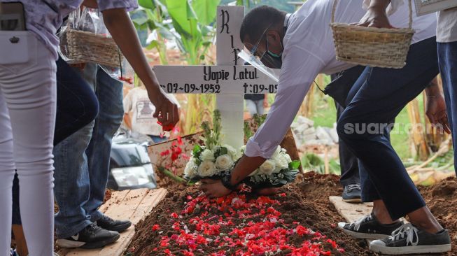 Keluarga dan kerabat menabur bunga di atas pusara Penyanyi Yopie Latul di TPU Tanah Kusir, Jakarta Selatan, Kamis (10/9). [Suara.com/Alfian Winanto]