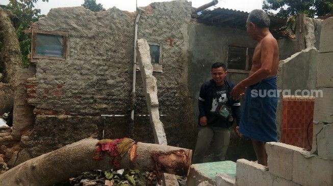 Warga Kampung Garahieum, Kecamatan Jayanti, Kabupaten Tangerang, sedang melihat kondisi rumahnya yang ambruk setelah tertiban pohon, Jumat (11/9/2020). [Suara.com/Ridsha Vimanda Nasution]