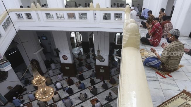 Sejumlah umat Muslim memanjatkan doa saat melaksanakan ibadah Shalat Jumat secara berjamaah di Masjid Cut Meutia, Jakarta, Jumat (11/9/2020). [Suara.com/Angga Budhiyanto]