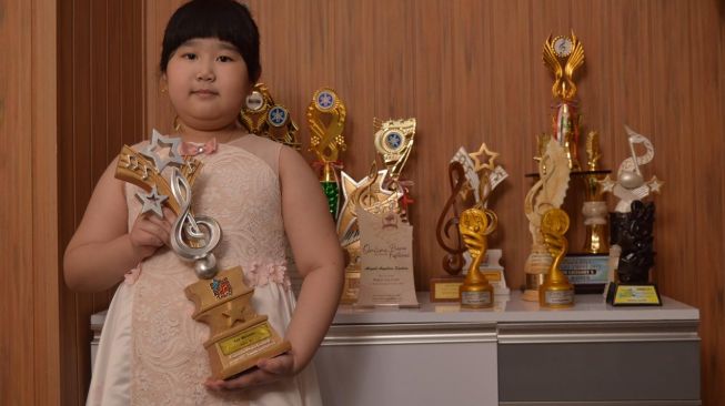 Abigail Angelica Santoso dengan sejumlah piala yang telah diraihnya. [dokumentasi pribadi]