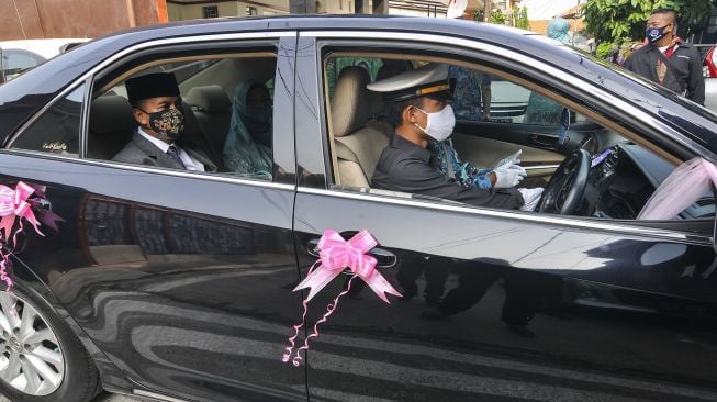 Pengantin menggunakan mobil dinas Pemerintah Kota Bekasi menuju lokasi pernikahan di Bekasi, Jawa Barat, Sabtu (12/9/2020). [ANTARA FOTO/ Fakhri Hermansyah]