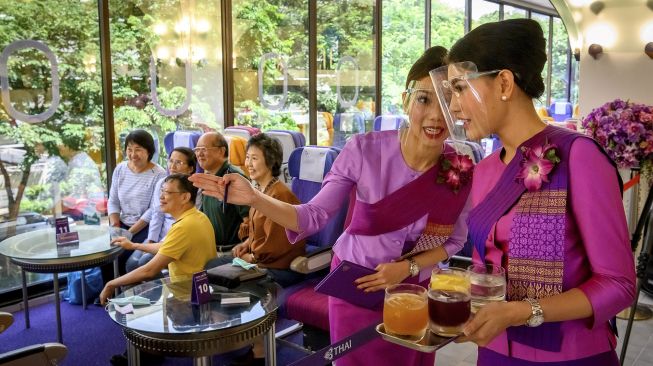 Pramugari Thai Airways mengenakan pelindung wajah saat melayani pelanggan di restoran bertema pesawat pop-up di kantor pusat maskapai penerbangan di Bangkok (10/9/2020). [Mladen ANTONOV / AFP]