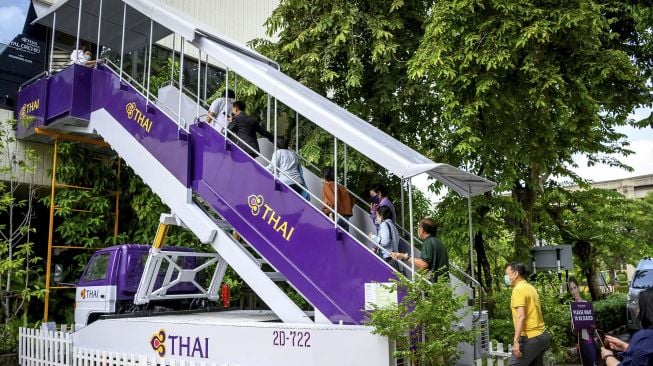 Sejumlah pengunjung menaiki jet brdige, yang biasanya digunakan oleh penumpang untuk naik pesawat, di restoran bertema pesawat pop-up Thai Airways di kantor pusat maskapai di Bangkok (10/9/2020). [Mladen ANTONOV / AFP]