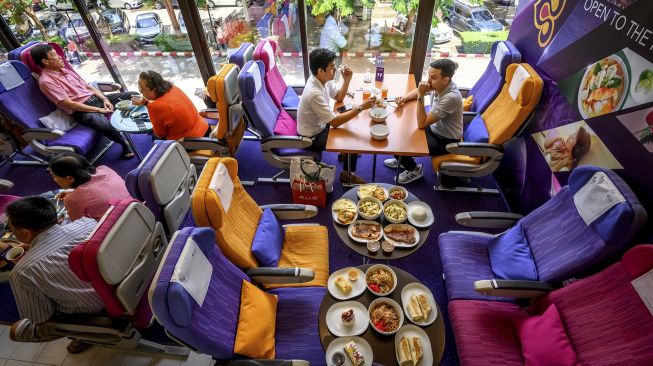 Sejumlah pengunjung duduk di kursi pesawat saat makan di restoran bertema pesawat pop-up Thai Airways di kantor pusat maskapai penerbangan di Bangkok (10/9/2020). [Mladen ANTONOV / AFP]