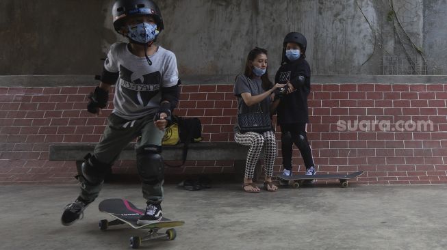 Orang tua membantu memasangkan pelindung tubuh kepada anaknya sebelum berlatih skateboard di Crooz School of Skate di kawasan Duren Tiga, Jakarta, Sabtu (12/9/2020). [Suara.com/Angga Budhiyanto]