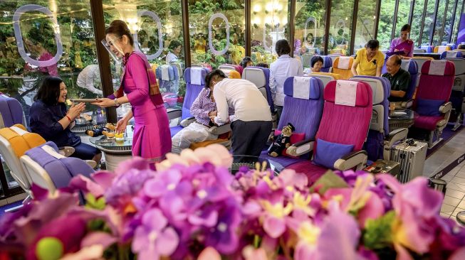 Seorang pramugari Thai Airways mengenakan pelindung wajah saat melayani pelanggan di restoran bertema pesawat pop-up di kantor pusat maskapai penerbangan di Bangkok (10/9/2020). [Mladen ANTONOV / AFP]