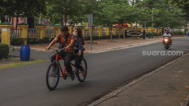 Warga bersepeda di Taman Mini Indonesia Indah, Jakarta Timur, Minggu (13/9). [Suara.com/Alfian Winanto]