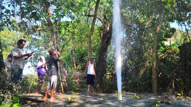 Warga menyaksikan semburan air dari sumur bor di Desa Manggarmas, Godong, Grobogan, Jawa Tengah, Minggu (13/9/2020). [ANTARA FOTO/Yusuf Nugroho]