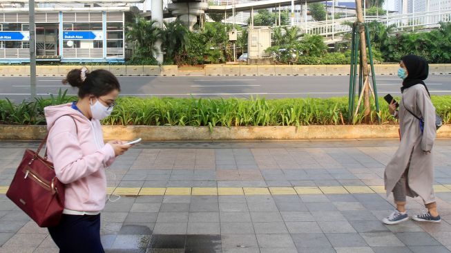 Warga melintas di trotoar jalan Sudirman, Jakarta, Senin (14/9). [Suara.com/Oke Atmaja]