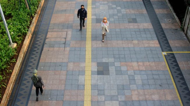 Warga melintas di trotoar jalan Sudirman, Jakarta, Senin (14/9). [Suara.com/Oke Atmaja]