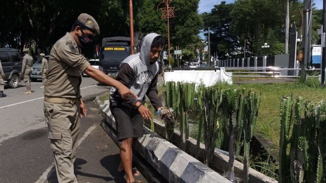 Tidak Pakai Masker, Warga Lhokseumawe Dihukum Cabuti Rumput di Bahu Jalan