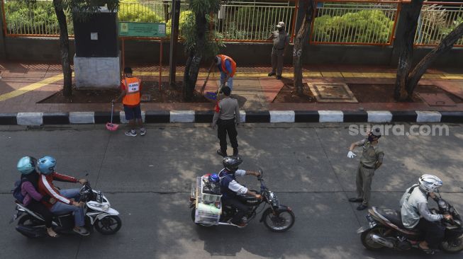 Dua warga yang terjaring operasi yustisi protokol kesehatan pencegahan Covid-19 karena tidak mengenakan masker menjalani sanksi sosial di jalan Taman Margasatwa, Jati padang, Jakarta Selatan, Selasa (15/9/2020). [Suara.com/Angga Budhiyanto]