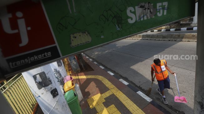 Seorang warga menyapu jalanan saat terjaring operasi yustisi protokol kesehatan pencegahan Covid-19 karena tidak mengenakan masker menjalani sanksi sosial di jalan Taman Marga Satwa, Jati padang, Jakarta Selatan, Selasa (15/9/2020). [Suara.com/Angga Budhiyanto]