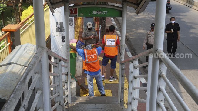 Dua warga yang terjaring operasi yustisi protokol kesehatan pencegahan Covid-19 karena tidak mengenakan masker menjalani sanksi sosial di jalan Taman Margasatwa, Jati padang, Jakarta Selatan, Selasa (15/9/2020). [Suara.com/Angga Budhiyanto]