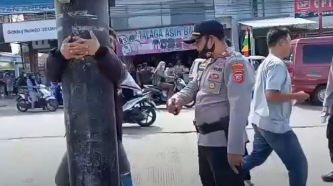 Seorang lelaki membuat heboh media maya karena dihukum peluk tiang listrik karena tak pakai masker.