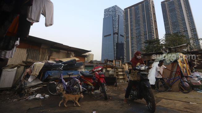 Warga beraktivitas dengan latar belakang deretan gedung perkantoran di permukiman padat penduduk di kawasan Menteng Pulo, Jakarta, Rabu (16/9/2020). [Suara.com/Angga Budhiyanto]