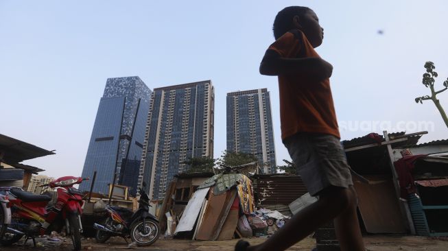 Seorang anak melintas dengan latar belakang deretan gedung perkantoran di permukiman padat penduduk di kawasan Menteng Pulo, Jakarta, Rabu (16/9/2020). [Suara.com/Angga Budhiyanto]