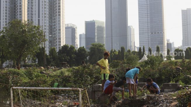 Sejumlah anak bermain dengan latar belakang deretan gedung perkantoran di TPU Menteng Pulo, Jakarta, Rabu (16/9/2020). [Suara.com/Angga Budhiyanto]