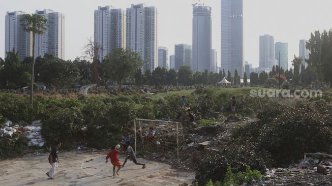 Sejumlah anak bermain sepakbola dengan latar belakang deretan gedung perkantoran di TPU Menteng Pulo, Jakarta, Rabu (16/9/2020). [Suara.com/Angga Budhiyanto]