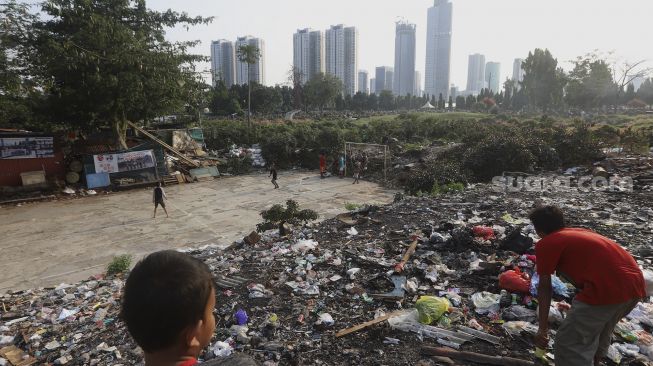 Sejumlah anak bermain dengan latar belakang deretan gedung perkantoran di TPU Menteng Pulo, Jakarta, Rabu (16/9/2020). [Suara.com/Angga Budhiyanto]