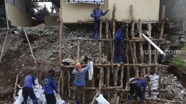 Petugas Suku Dinas Sumber Daya Air Jakarta Selatan membangun kembali turap yang longsor di Rumah Pohon Jagakarsa, Jakarta, Kamis (17/9/2020). [Suara.com/Angga Budhiyanto]