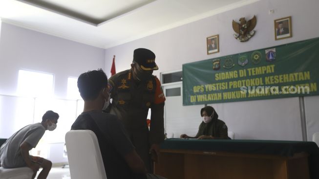 Warga pelanggar PSBB mengikuti sidang di tempat usai terjaring operasi yustisi protokol kesehatan pencegahan Covid-19 di SMKN 57 Jakarta, Kamis (17/9/2020). [Suara.com/Angga Budhiyanto]