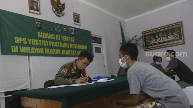 Warga pelanggar PSBB mengikuti sidang di tempat usai terjaring operasi yustisi protokol kesehatan pencegahan Covid-19 di SMKN 57 Jakarta, Kamis (17/9/2020). [Suara.com/Angga Budhiyanto]