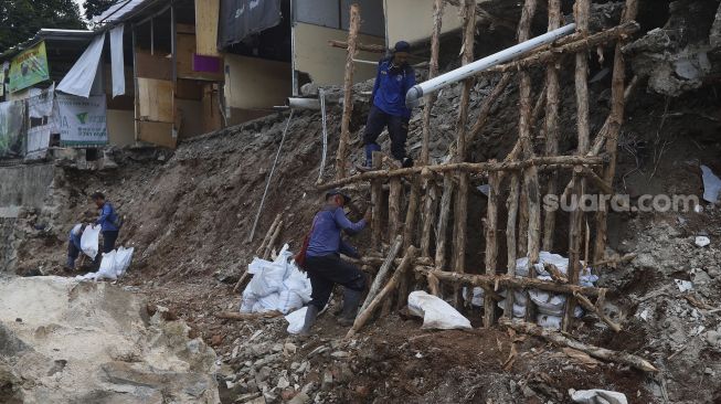 Petugas Suku Dinas Sumber Daya Air Jakarta Selatan membangun kembali turap yang longsor di Rumah Pohon Jagakarsa, Jakarta, Kamis (17/9/2020). [Suara.com/Angga Budhiyanto]