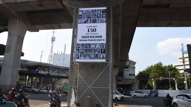 Pengendara melintas di dekat videotron yang menampilkan jumlah tenaga kesehatan yang menjadi korban COVID-19 di kawasan Kebayoran Baru, Jakarta, Jumat (18/9/2020).  [ANTARA FOTO/Indrianto Eko Suwarso]
