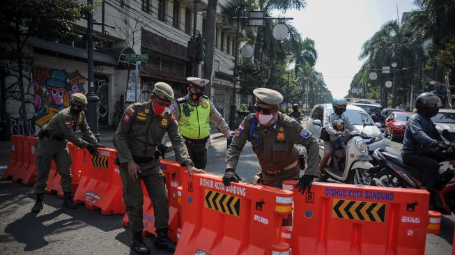 Petugas kepolisian bersama Satpol PP menutup jalan Asia Afrika, Bandung, Jawa Barat, Jumat (18/9/2020). [ANTARA FOTO/Raisan Al Farisi]
