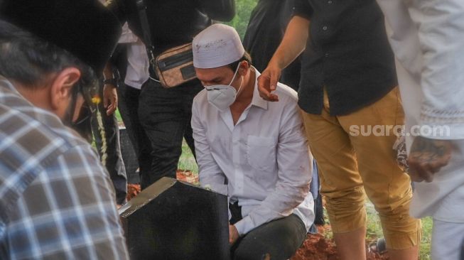 Aktor Indra Bruggman menatap pusara sang Ibu saat dimakamkan di TPU Menteng Pulo I, Jakarta Selatan, Jumat (18/9). [Suara.com/Alfian Winanto]